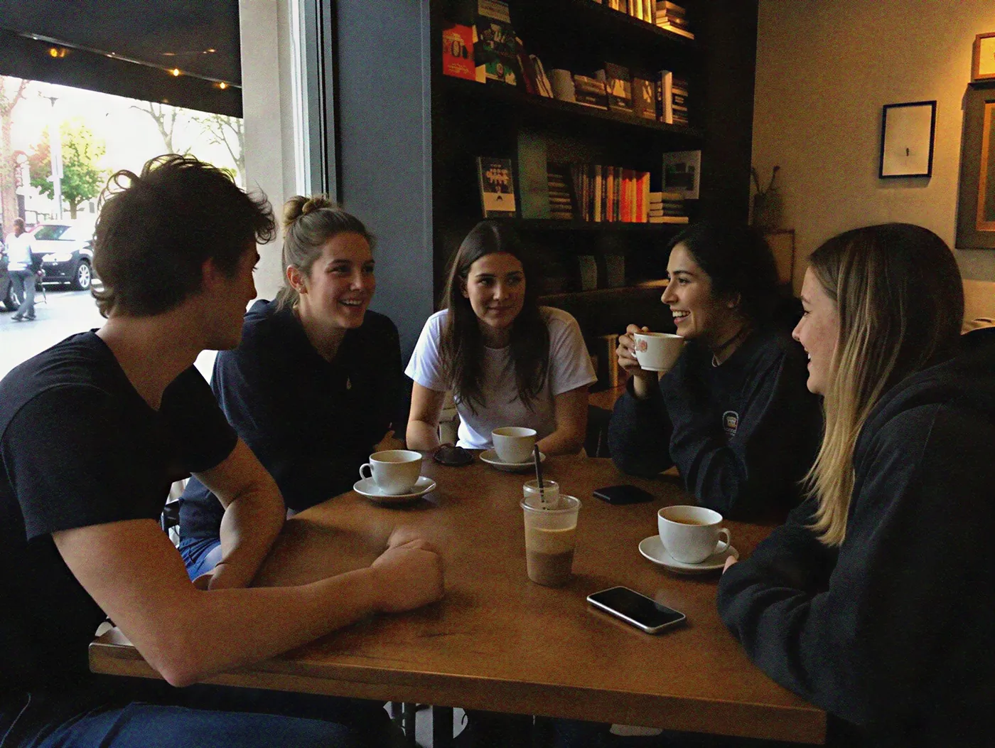 A group of friends laughing together over coffee at a cafe.