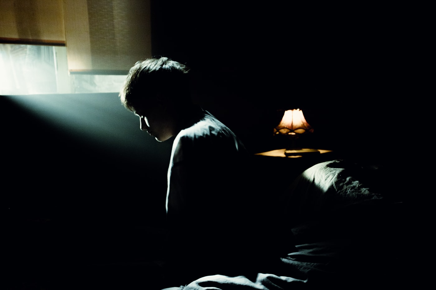 A person awake on a bed in a dark room at night