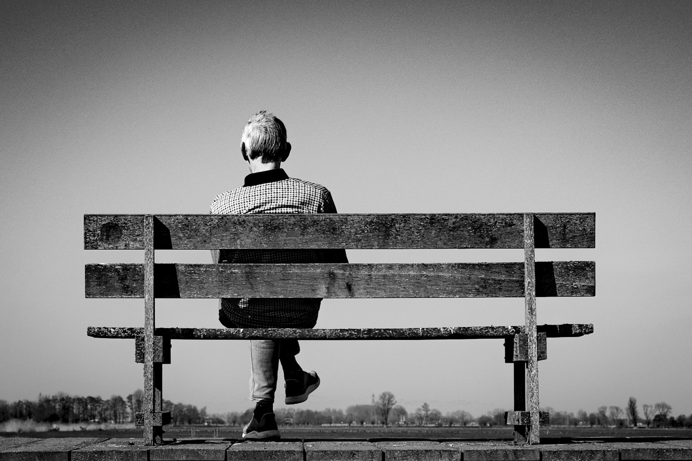 A person sitting alone on a bench apart from others